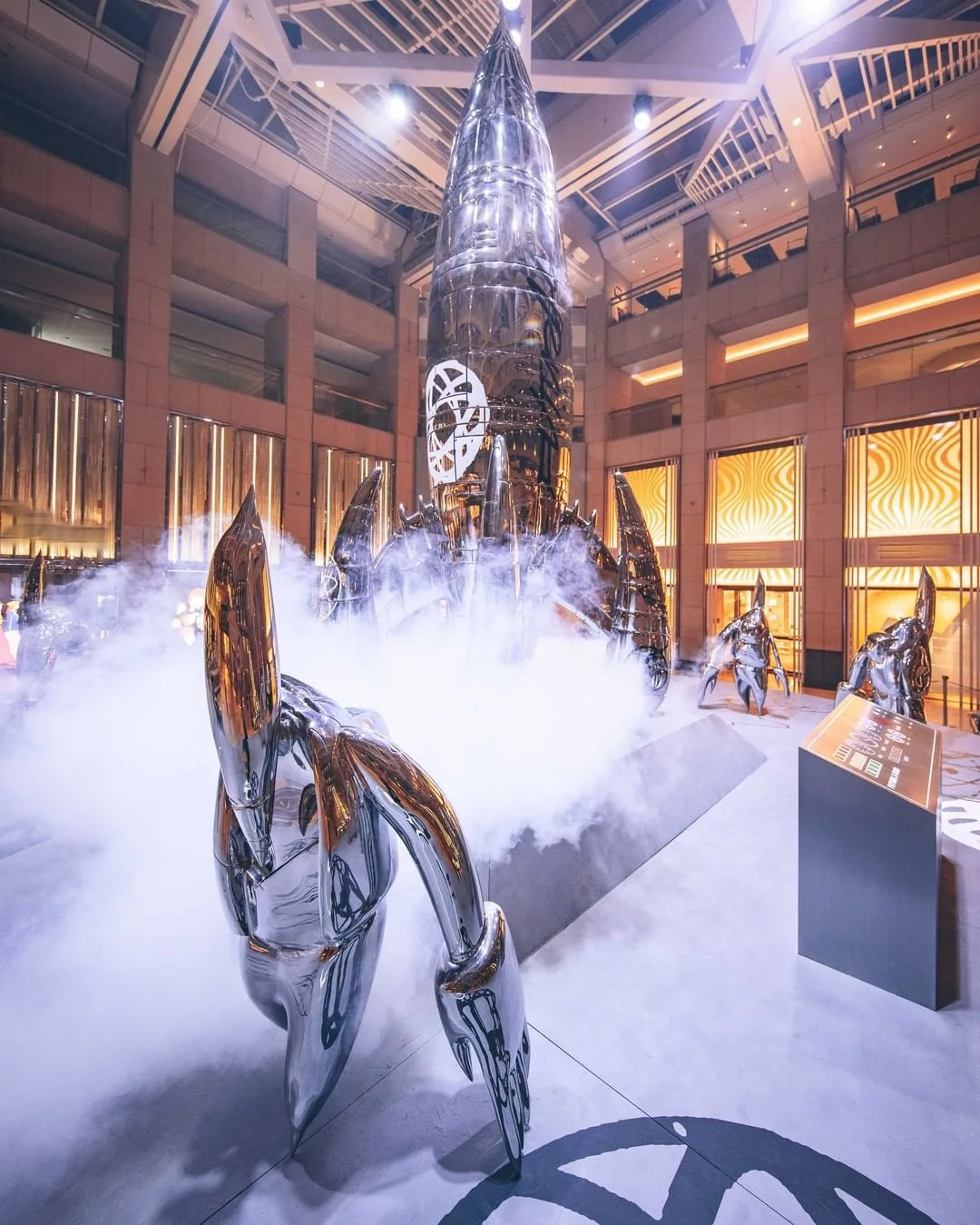 Installation view, FUTURALAND, 2021. A single FL-006 figure in the foreground, vapour across the atrium floor.